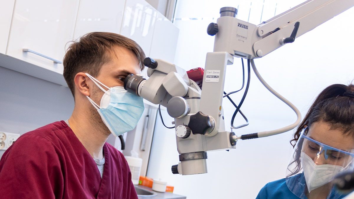 Leczenie kanałowe pod mikroskopem we Wrocławiu – stomatolog endodonta wykonuje precyzyjny zabieg endodontyczny z asystentką
